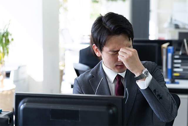 眉間に手を当てている男性